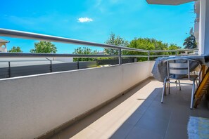 A balcony with a metal railing, a covered table, and a chair. - Apartment Agi (Kastela)