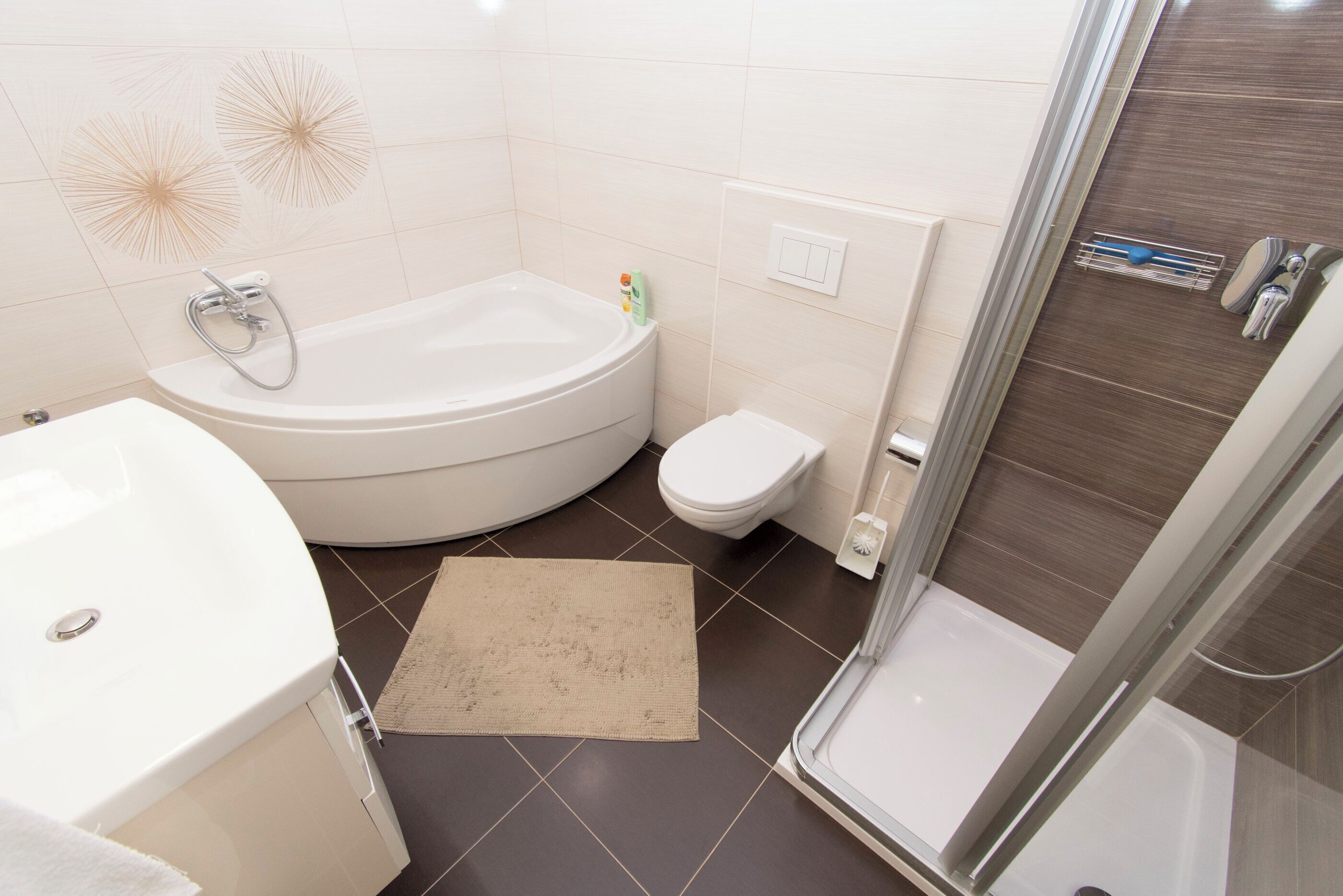 Et moderne badeværelse med badekar, toilet og brusebad.