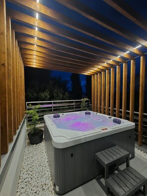 A hot tub under a wooden pergola with a railing and potted plants. - Apartment Jasna (Supetar)