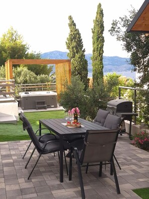 An outdoor patio with a table and chairs, a grill, and a view of the mountains. - Apartment Jasna (Supetar)