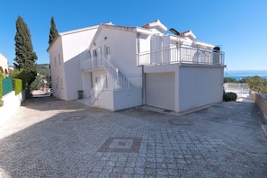 Un edificio su due piani con un balcone, una scala e un garage.
