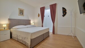 A bedroom with a bed, bedside tables, a picture on the wall, and a coat rack. - Apartments Kati (Seget)