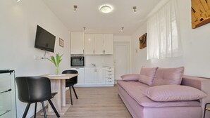 A compact living space with a kitchenette, a dining area, and a seating area with a sofa. - Apartments Kati (Seget)