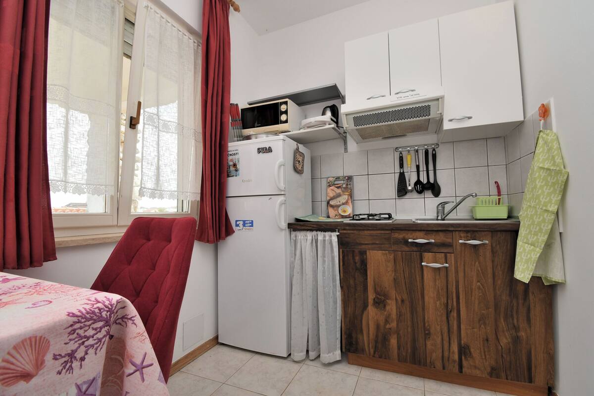 Eine kleine Küche mit Kühlschrank, Mikrowelle und Holzschränken.