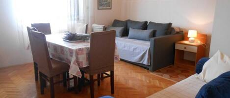 A cozy room with a dining table, chairs, a sofa, and a bed.
