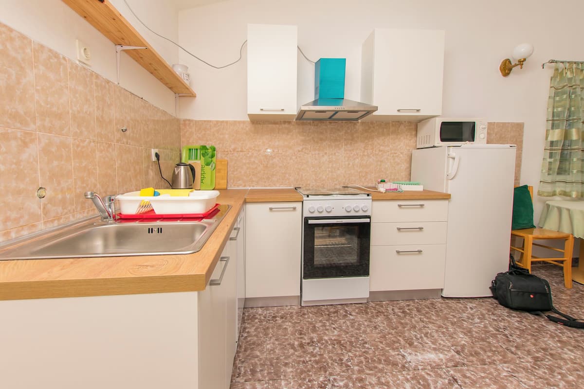 A compact kitchen with a sink, stove, microwave, and refrigerator.