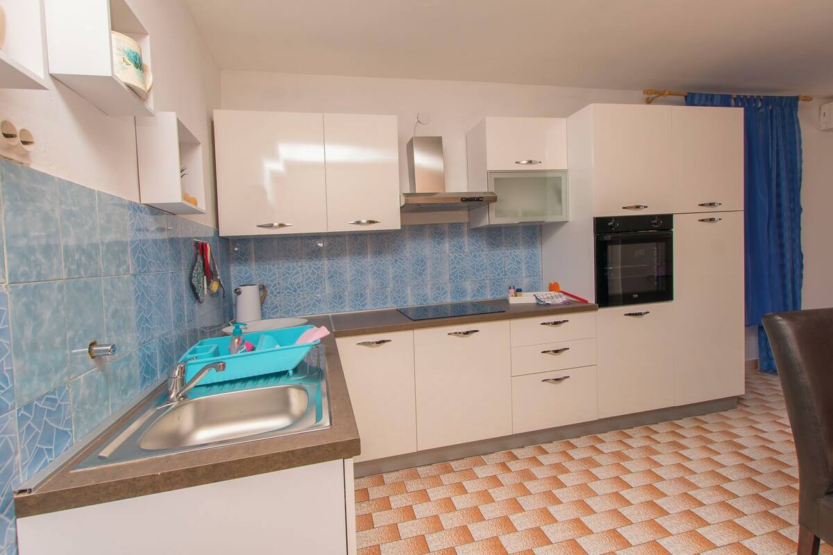A kitchen with white cabinets, a sink, and a blue tiled backsplash.