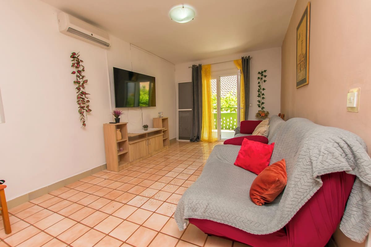 A living room with a sofa, TV, and a sliding door leading to a balcony.