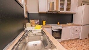 A kitchen with a stainless steel sink, a stove, and white cabinets. - Apartments Selma (Biograd na Moru)