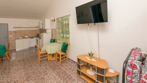 A compact living space with a dining area, kitchenette, and a TV mounted on the wall. - Apartments Selma (Biograd na Moru)