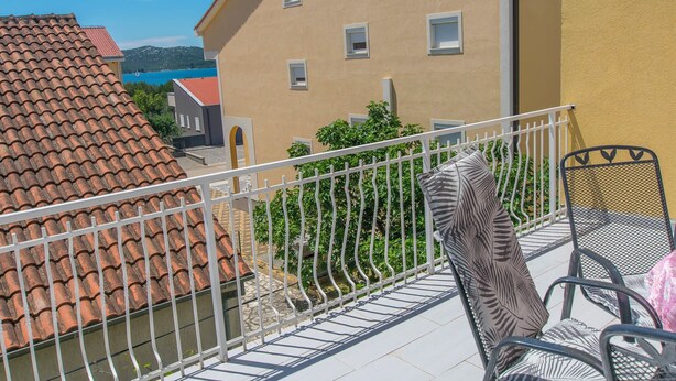 A balcony with metal railings, a chair, and a table. - Apartments Selma (Biograd na Moru)