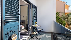 A balcony with a table and chairs, a sliding glass door, and a view of a building. - Apartments Andrea (Sibenik)