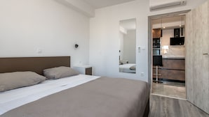 A modern hotel room with a large bed, a bedside table, and a mirror. - Apartments Andrea (Sibenik)
