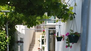 A narrow alleyway with a staircase leading to a building entrance, surrounded by white walls and potted plants. - Apartments Mare (Brela)