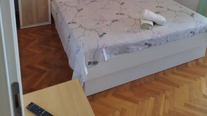 A bedroom with a bed, a small table, and a hanging light fixture. - Apartments Mare (Brela)