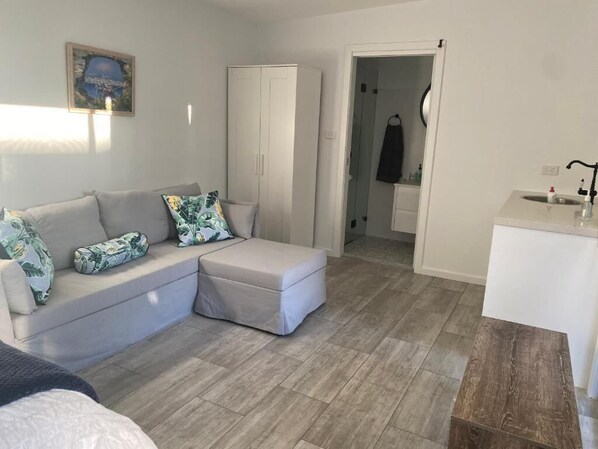 Un salon moderne avec un canapé d’angle, une petite table en bois et une armoire blanche.