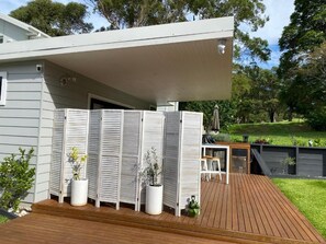A modern house with a wooden deck, white shutters, and potted plants. - Golf Course & Beach Stay Self-contained Guest House (Nelson Bay)