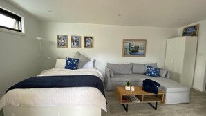 Quarto com uma cama, um sofá cinzento, uma mesa de centro de madeira e um guarda-roupa.