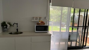 Cozinha moderna com pia embutida, micro-ondas e janela com vista para o quintal.
