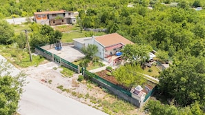 Una zona residenziale con una casa caratterizzata da un tetto in tegole rosse, un cortile recintato e un piccolo giardino.