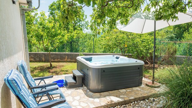 A hot tub, lounge chairs, and a stone patio with a garden view. - House Tamy - With Jacuzzi (Omis)