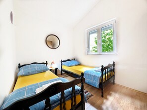 A room with two single beds, a round mirror, and a window with a view of greenery. - House Tamy - With Jacuzzi (Omis)
