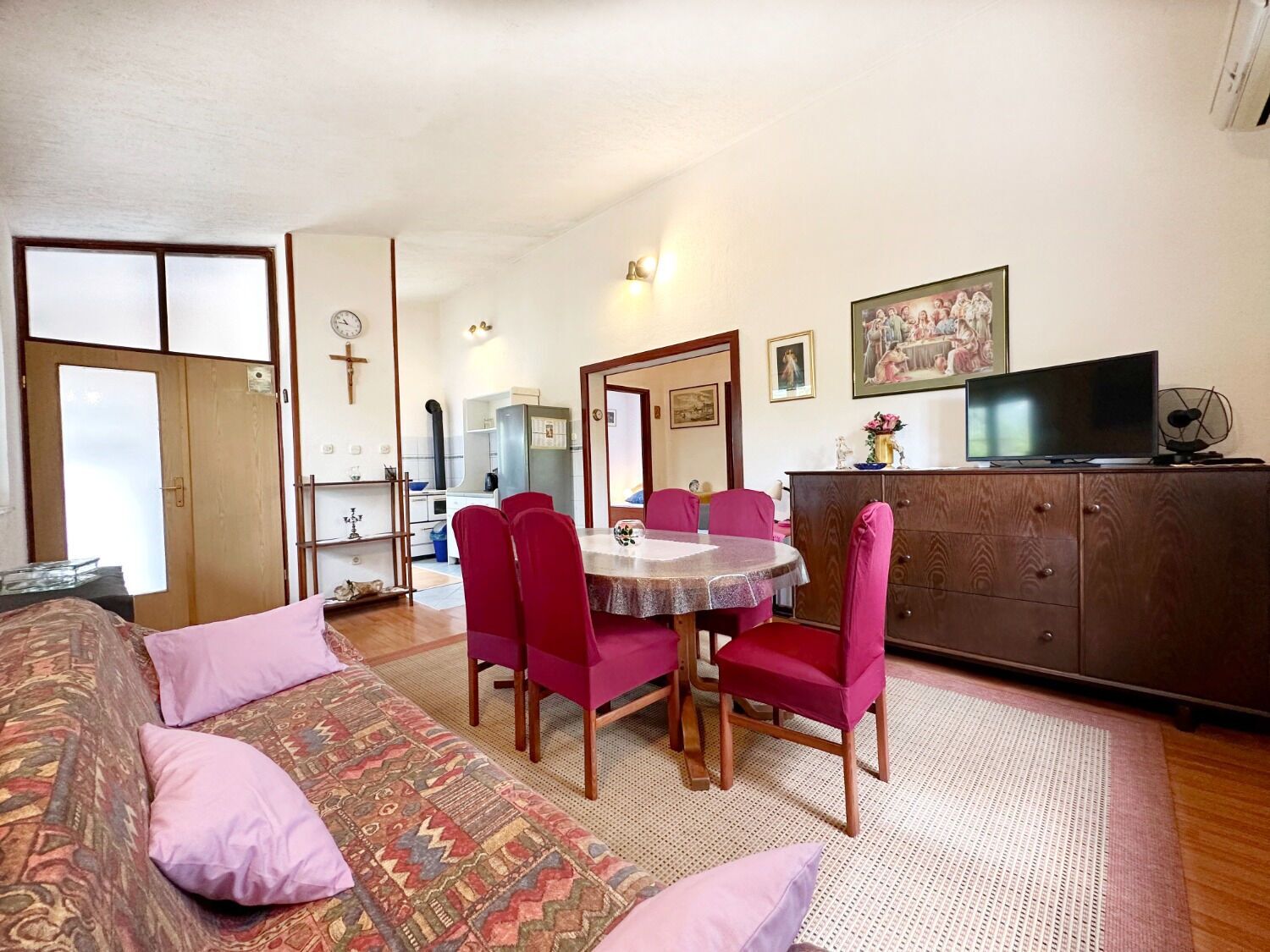 A cozy room with a bed, a dining table with chairs, a television, and a cabinet.