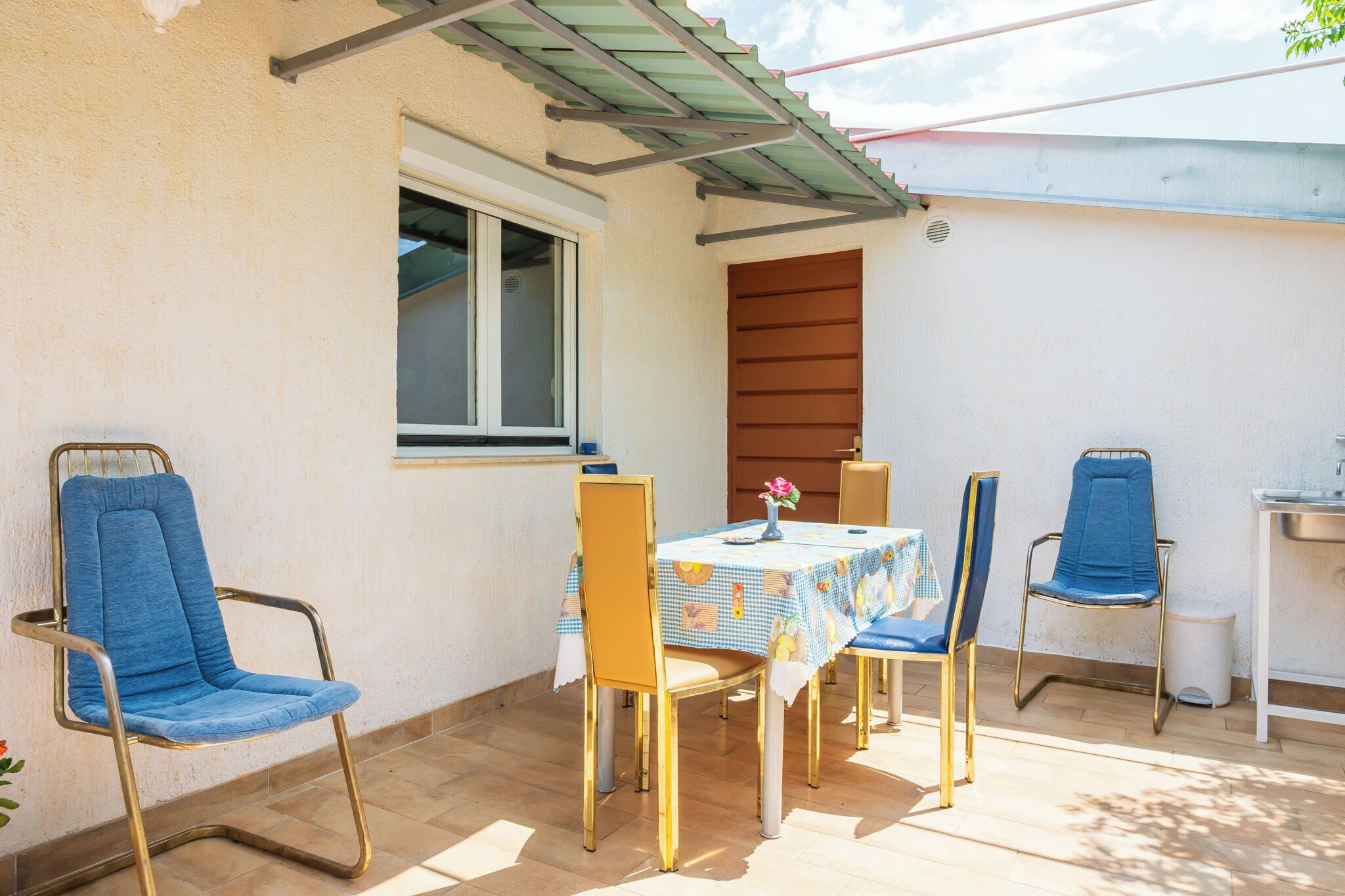 An outdoor patio with a table, chairs, and a window.
