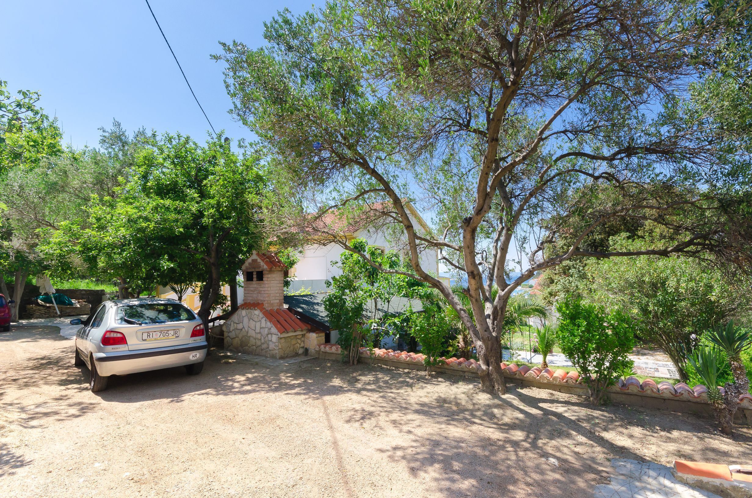 A car parked in front of a house with a stone wall and a small garden.