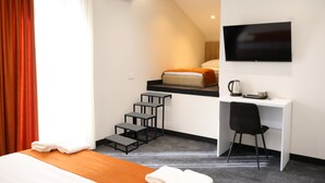 A hotel room with a bed, a desk, a chair, a TV, and a staircase. - New Casa  (Yerevan)
