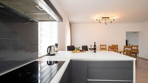 A modern kitchen with a central island, a built-in oven, and a stainless steel range hood. - Apartment Val (Okrug)