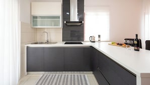 A modern kitchen with a built-in stove, a sink, and a window. - Apartment Val (Okrug)