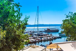 A marina with boats docked, surrounded by trees and a clear sky. - Apartments and Rooms Hope (Brela)