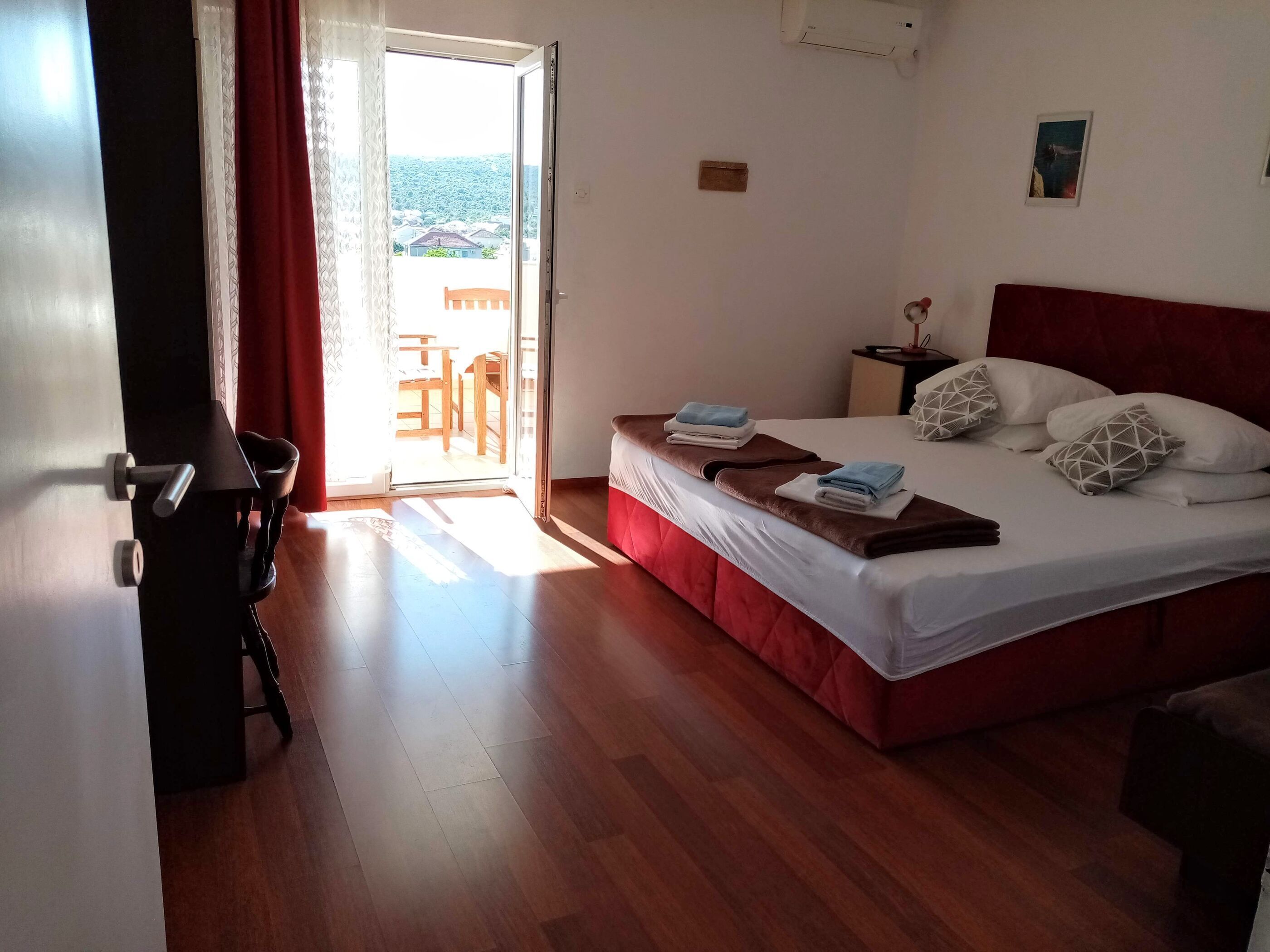 Une chambre à coucher avec un lit, une table de chevet, une chaise et une vue sur l’extérieur.