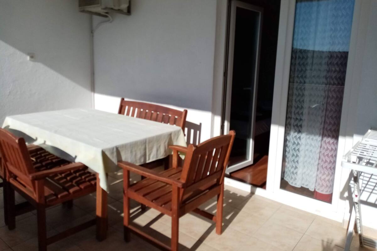 A dining area with a table and chairs, a sliding glass door, and a window with patterned curtains.