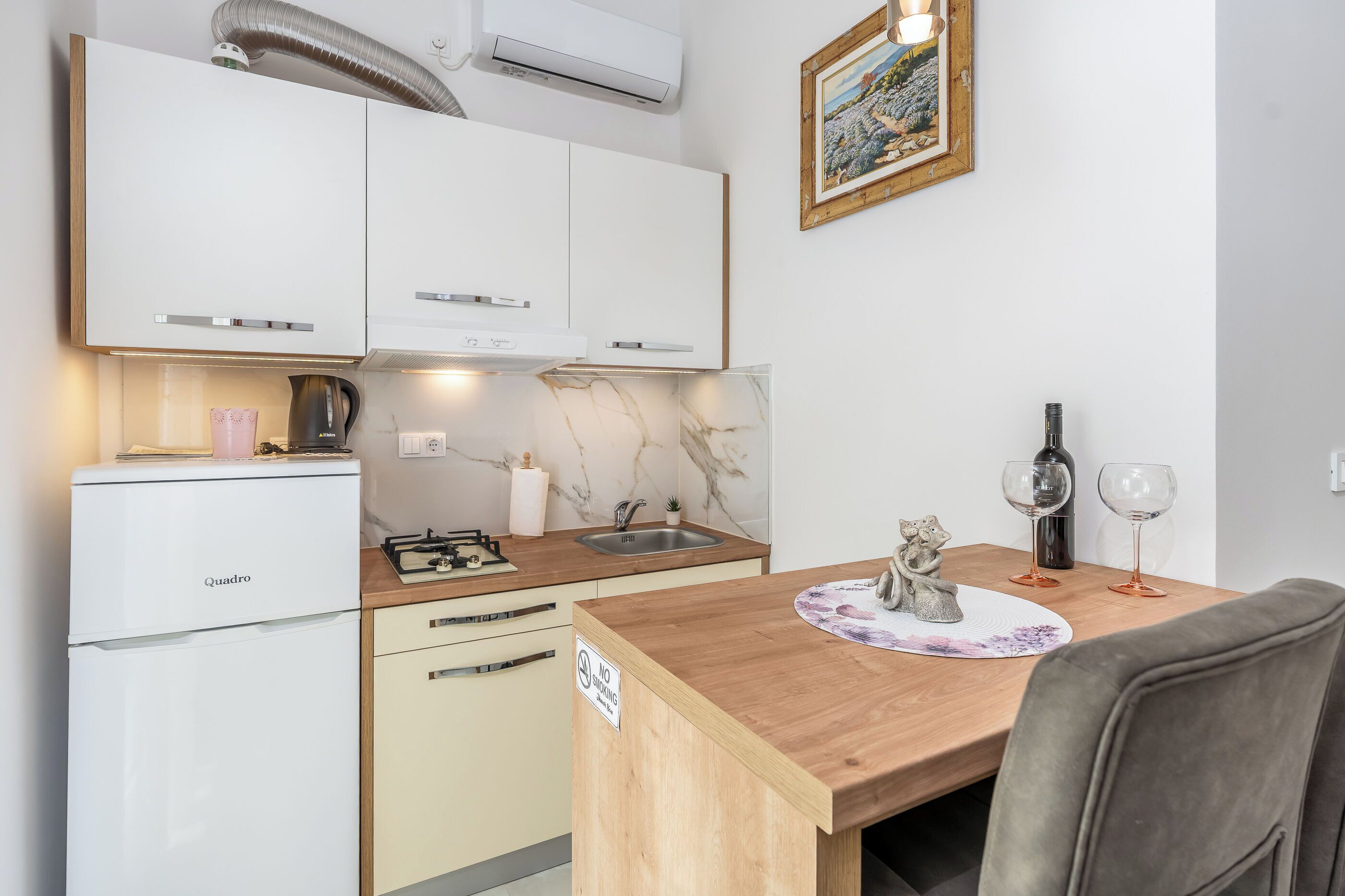 A compact kitchen with a refrigerator, stove, sink, and a dining area with a table and chairs.