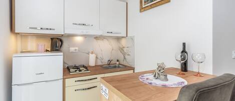 A compact kitchen with a refrigerator, stove, sink, and a dining area with a table and chairs.