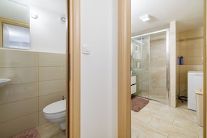 A modern bathroom with a toilet, sink, and shower area. - Apartments Jadro (Crikvenica)