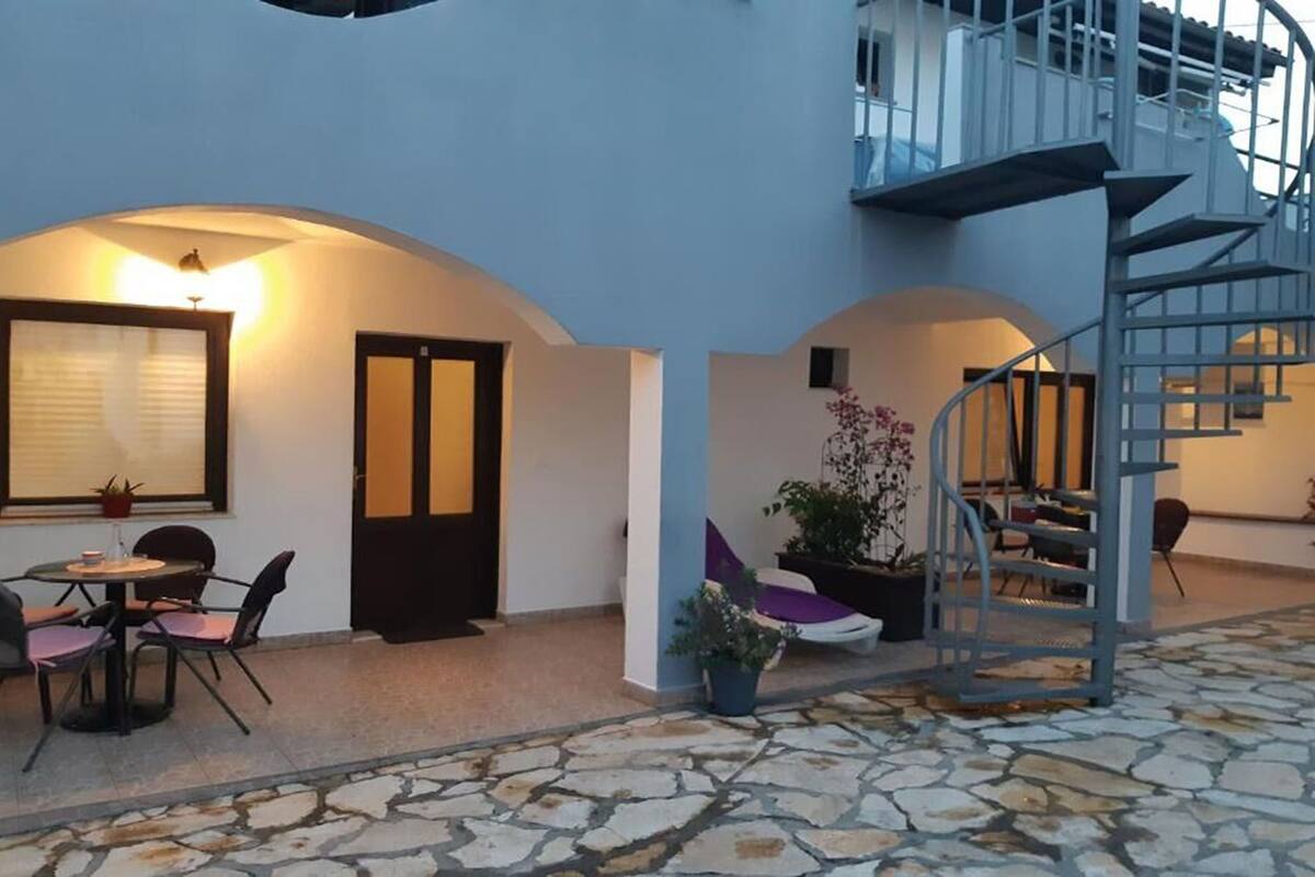 A courtyard with a dining area, a staircase, and a potted plant.