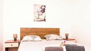 Ein ordentlich bezogenes Bett mit zwei Kissen, einem Holzkopfbrett und zwei Nachttischen mit Lampen.