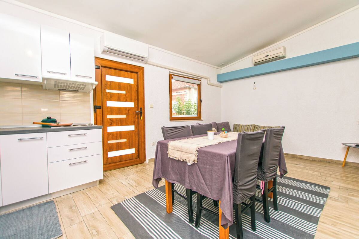 A modern kitchen with white cabinets, a wooden door, and a window.