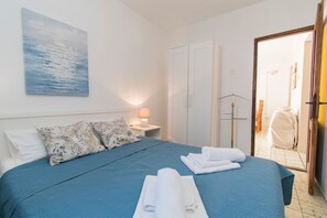 Una habitación de hotel con cama, armario, espejo y un cuadro en la pared.