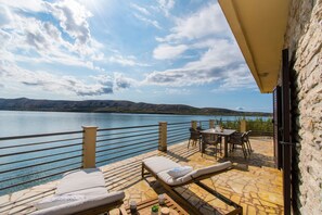 Una terraza con sillones, una mesa y vistas a un lago y montañas.