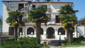A two-story building with a sign indicating a restaurant on the ground floor. - Apartments Lion (Umag)