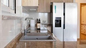 Een moderne keuken met een roestvrijstalen spoelbak, een inbouwoven en een koelkast met waterdispenser.