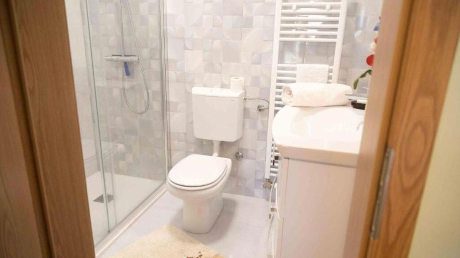 Une salle de bain avec une douche à parois de verre, des toilettes et un lavabo avec une serviette posée sur le comptoir.