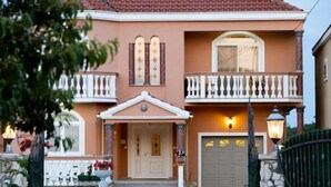 Een huis met twee verdiepingen, een balkon, een garage en een verzorgde voortuin.