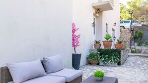 A patio with a wicker sofa, a small table, and potted plants.