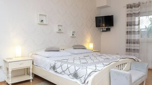 A bedroom with a bed, bedside tables, a TV, and a window with curtains.