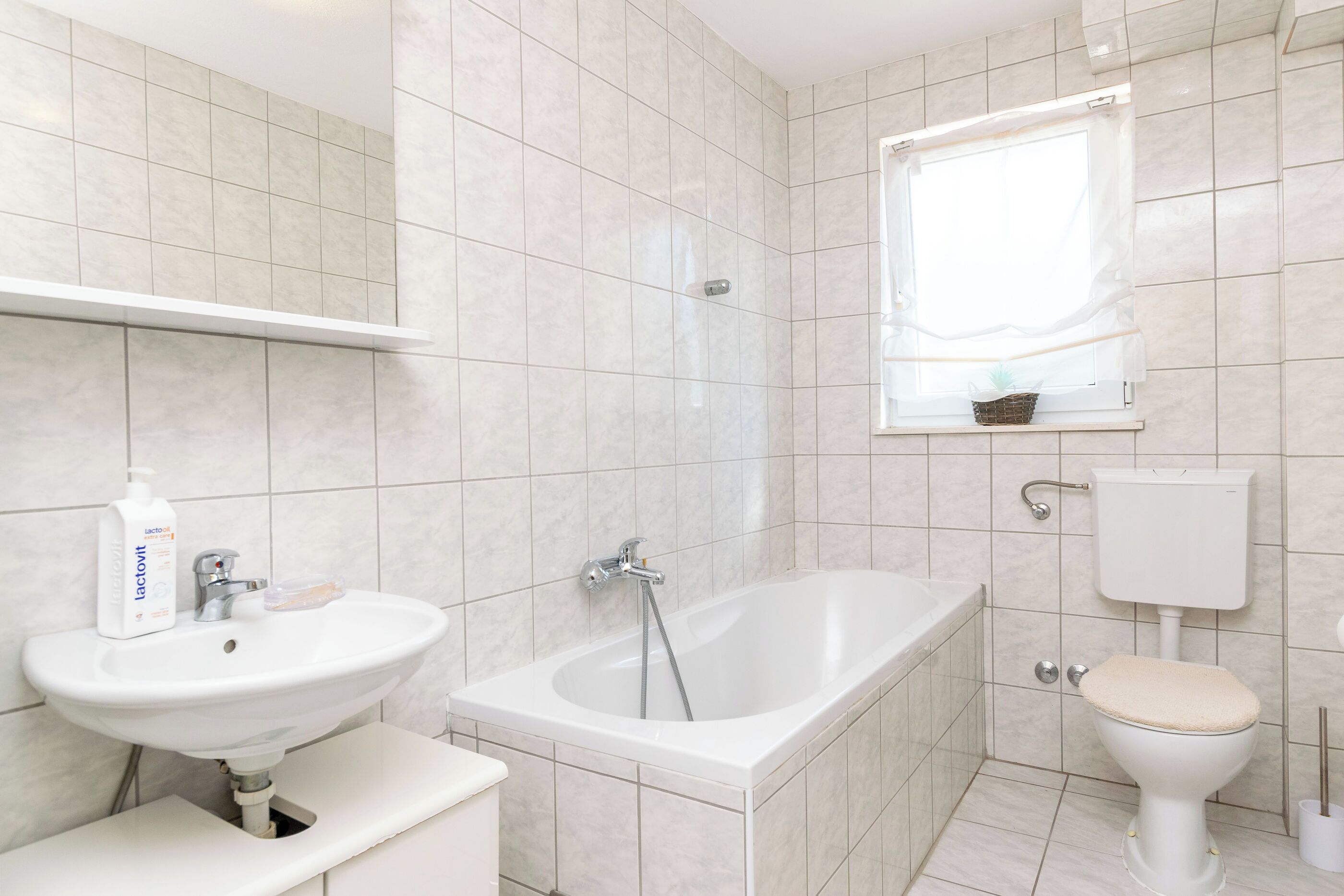 A modern bathroom with a white sink, bathtub, and toilet.